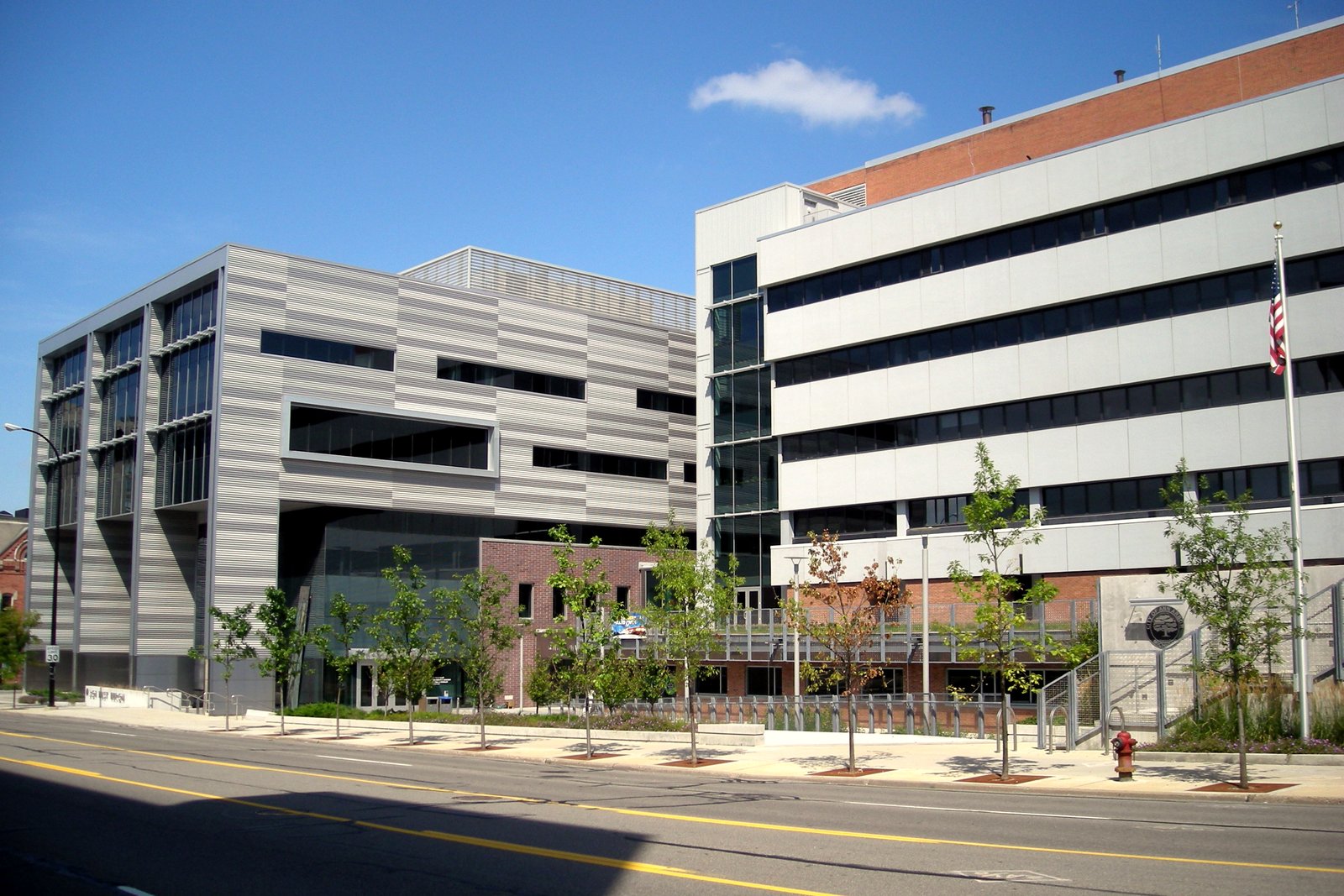 Ann Arbor City Hall, a gray and white multistory office building with a newer metal-clad addition, seen from a street on a sunny day.