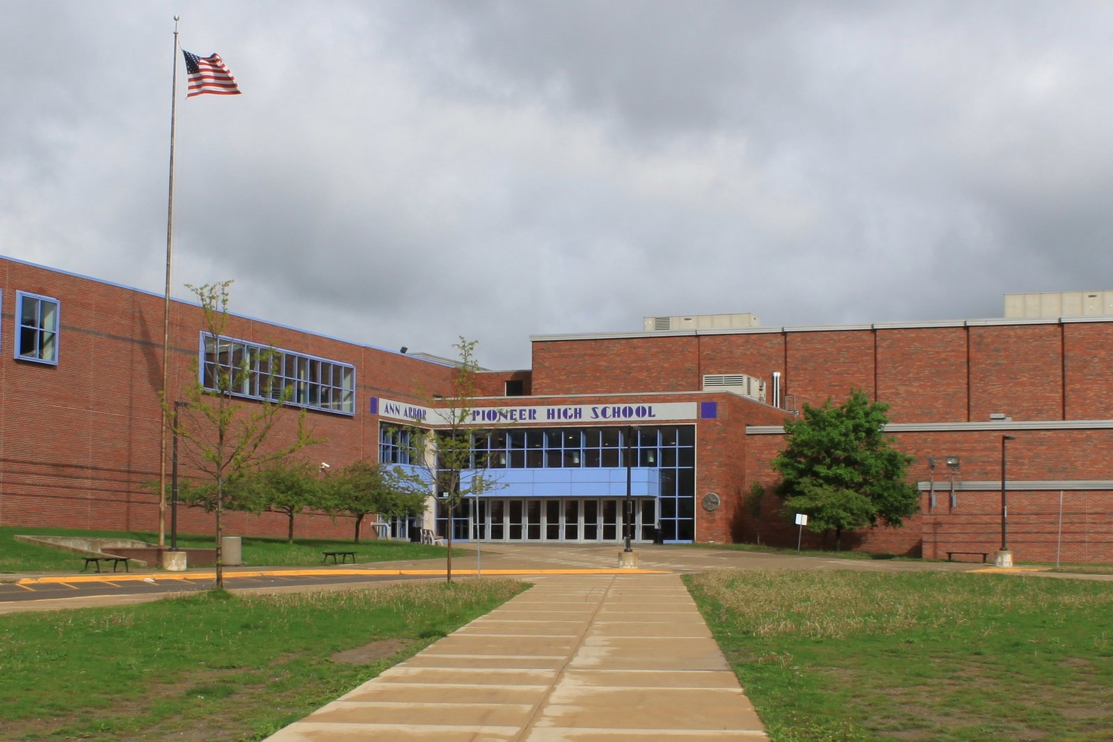 The front entrance of Pioneer High School in Ann Arbor, with its name over the doors and a flagpole on the lawn.