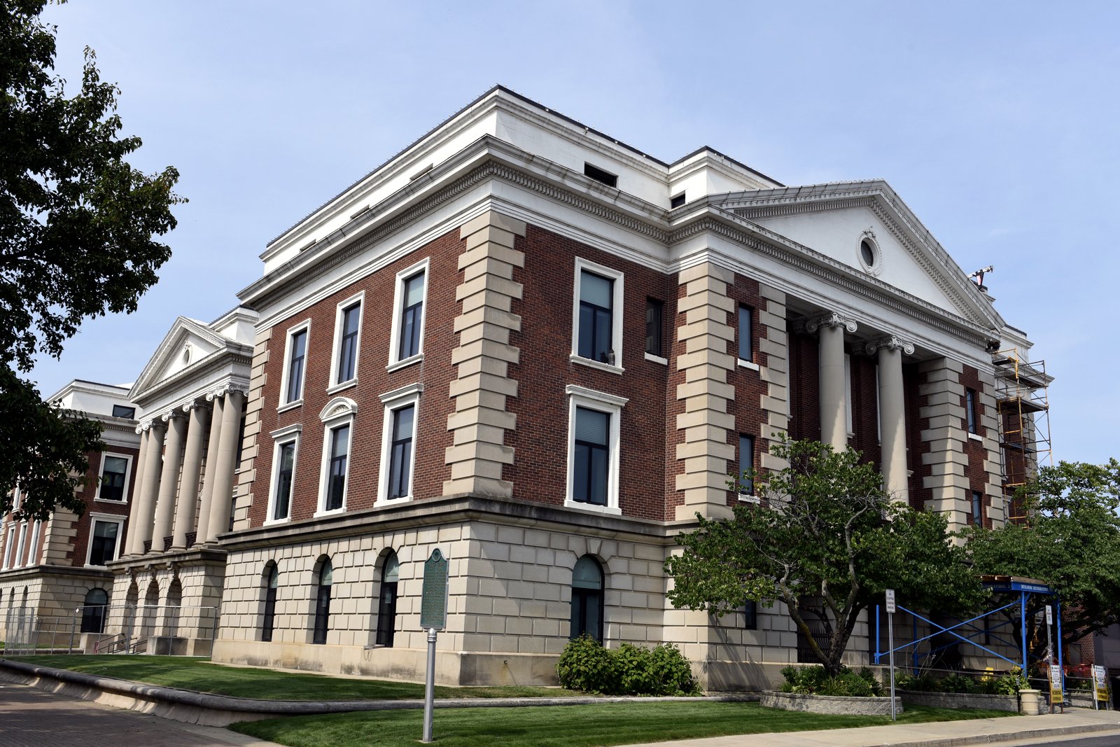 The stone facade and clock tower of Battle Creek City Hall on a clear day.