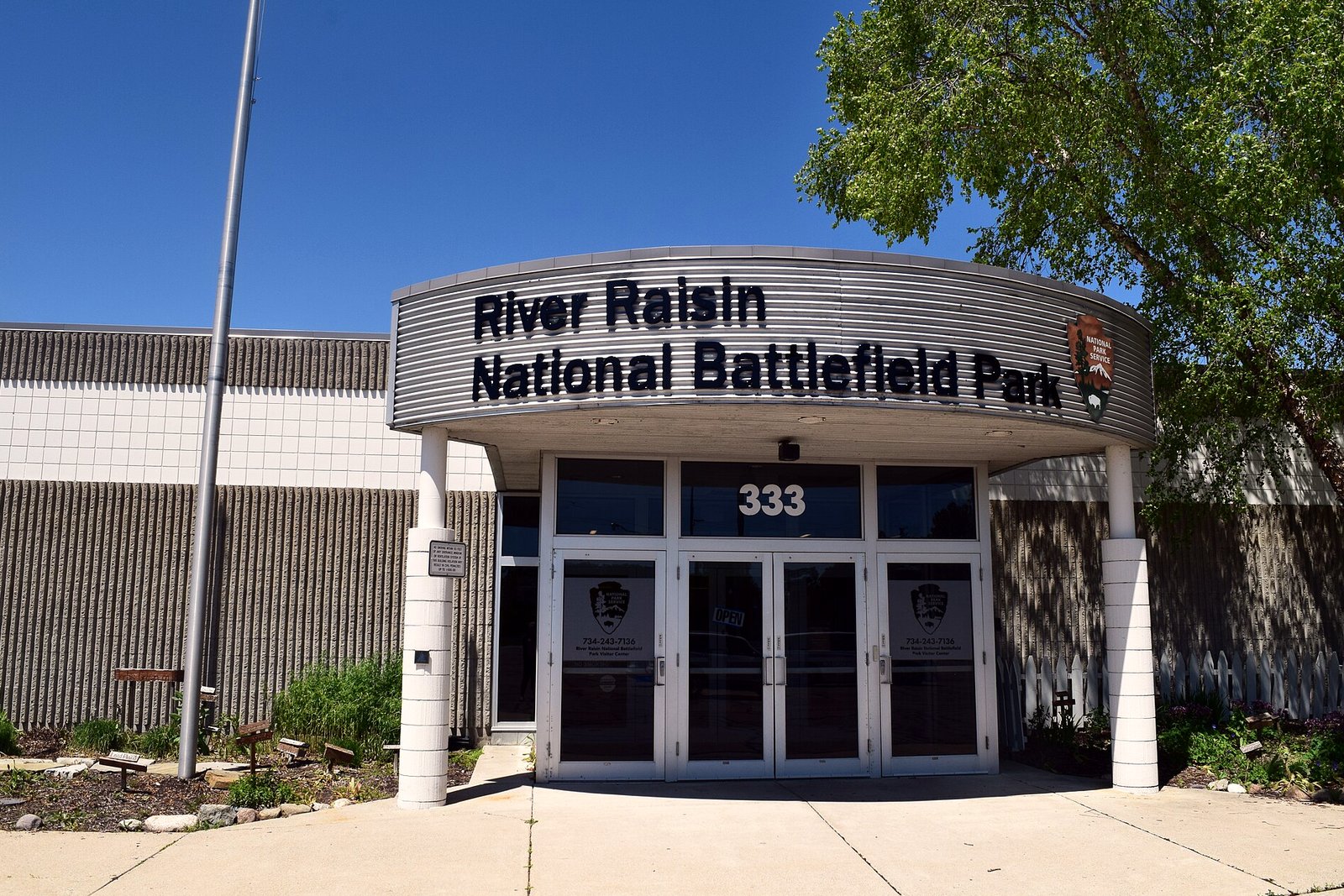 The entrance of the River Raisin National Battlefield Park visitor center, with the park name on a curved sign above glass doors marked 333.