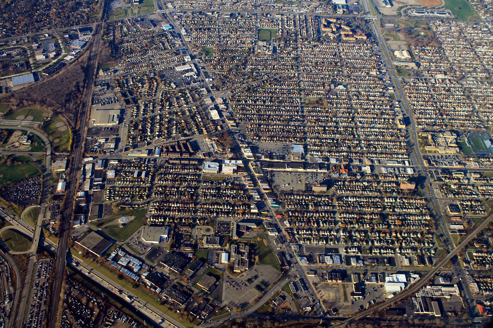 An aerial view of a dense grid of neighborhoods and wide boulevards stretching to the horizon.