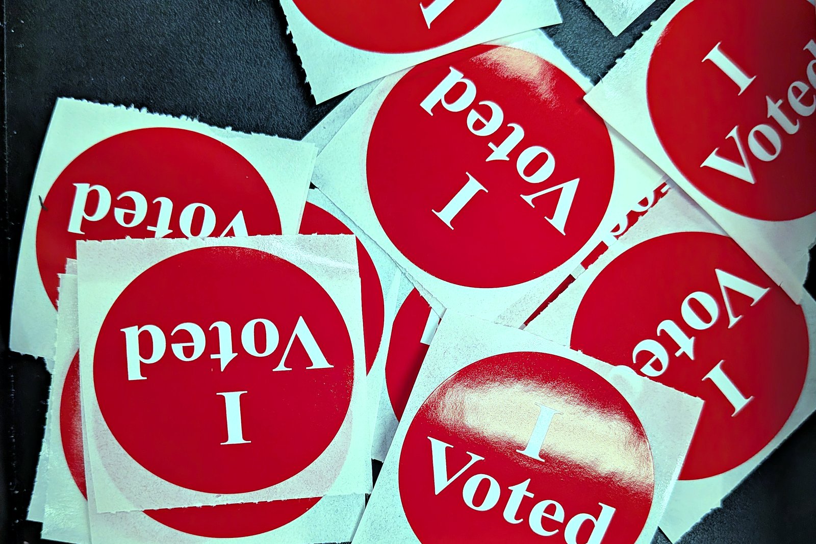 A scattered pile of round red-white-and-blue I Voted stickers.