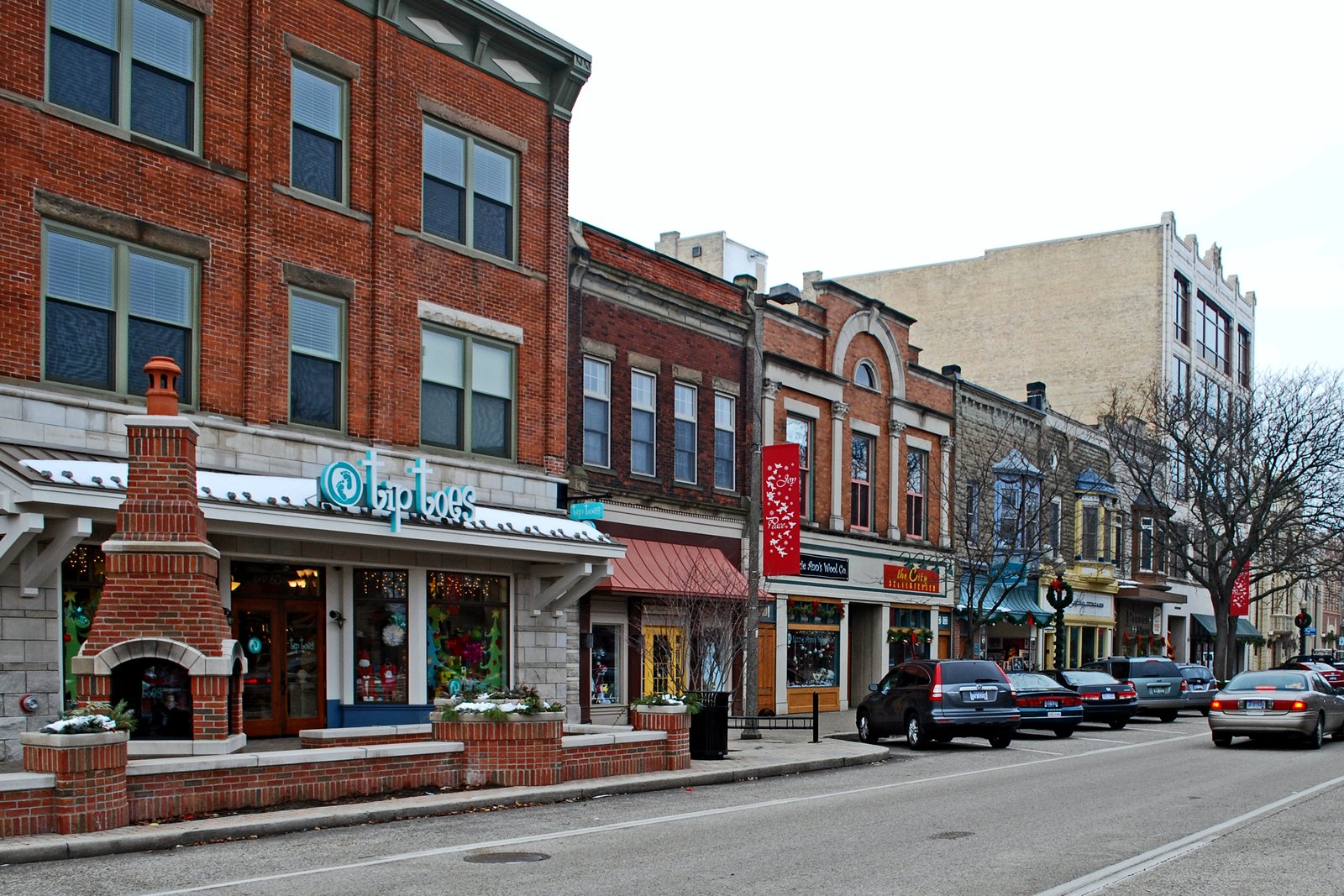 A downtown street of two- and three-story historic brick commercial buildings with storefronts and parked cars.
