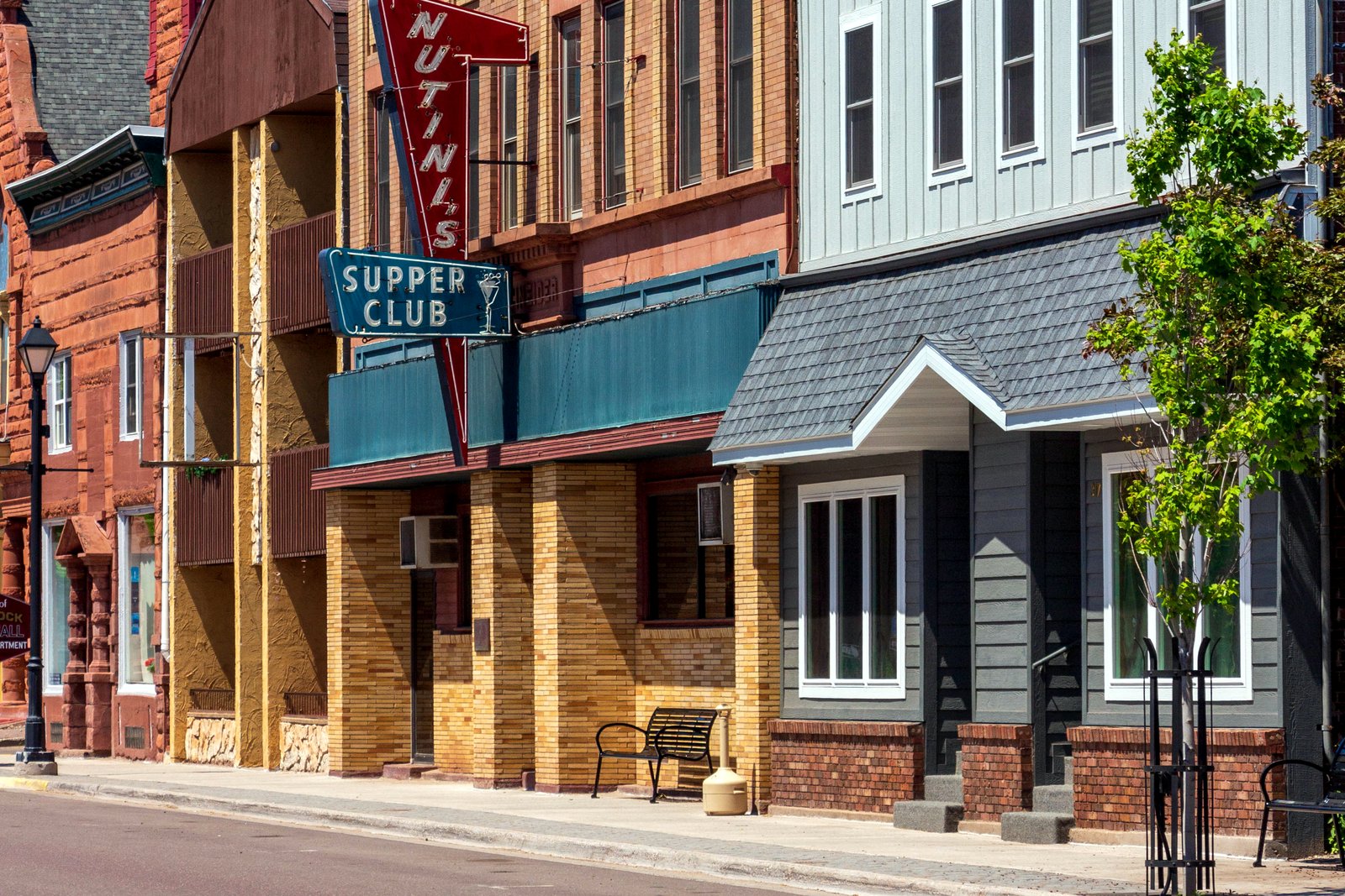 Quincy Street in downtown Hancock, lined with brick storefronts, sloping toward the Portage Canal on a summer day.