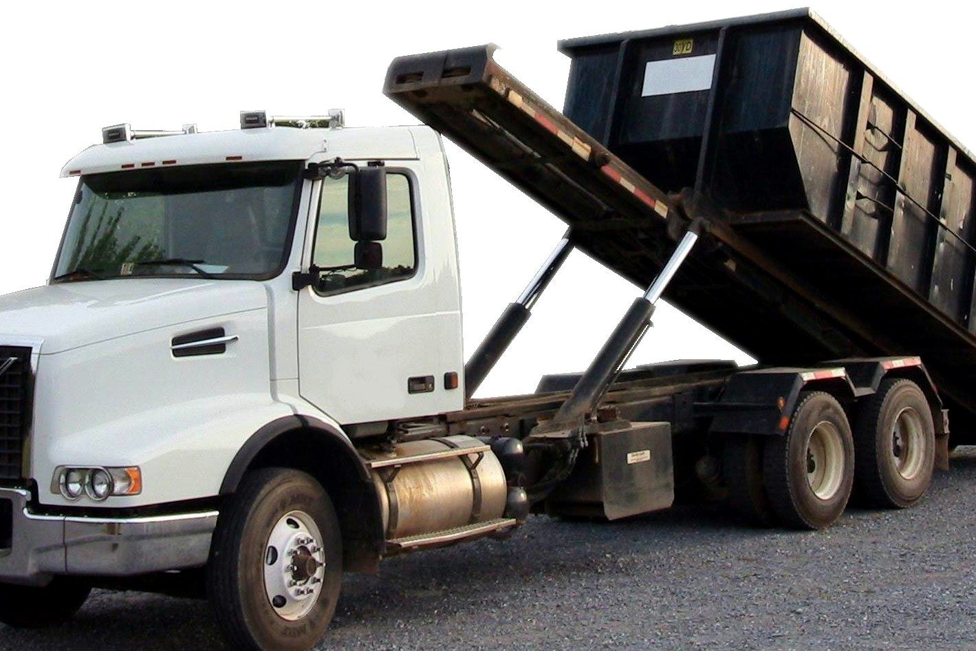 A white roll-off truck carrying a large green dumpster container parked on pavement.
