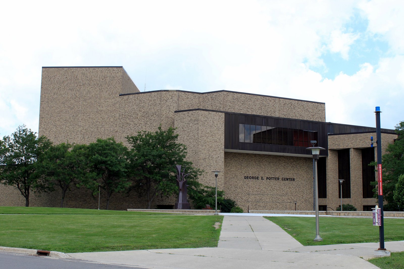 The tan brick George E. Potter Center on the Jackson College campus under a partly cloudy summer sky.