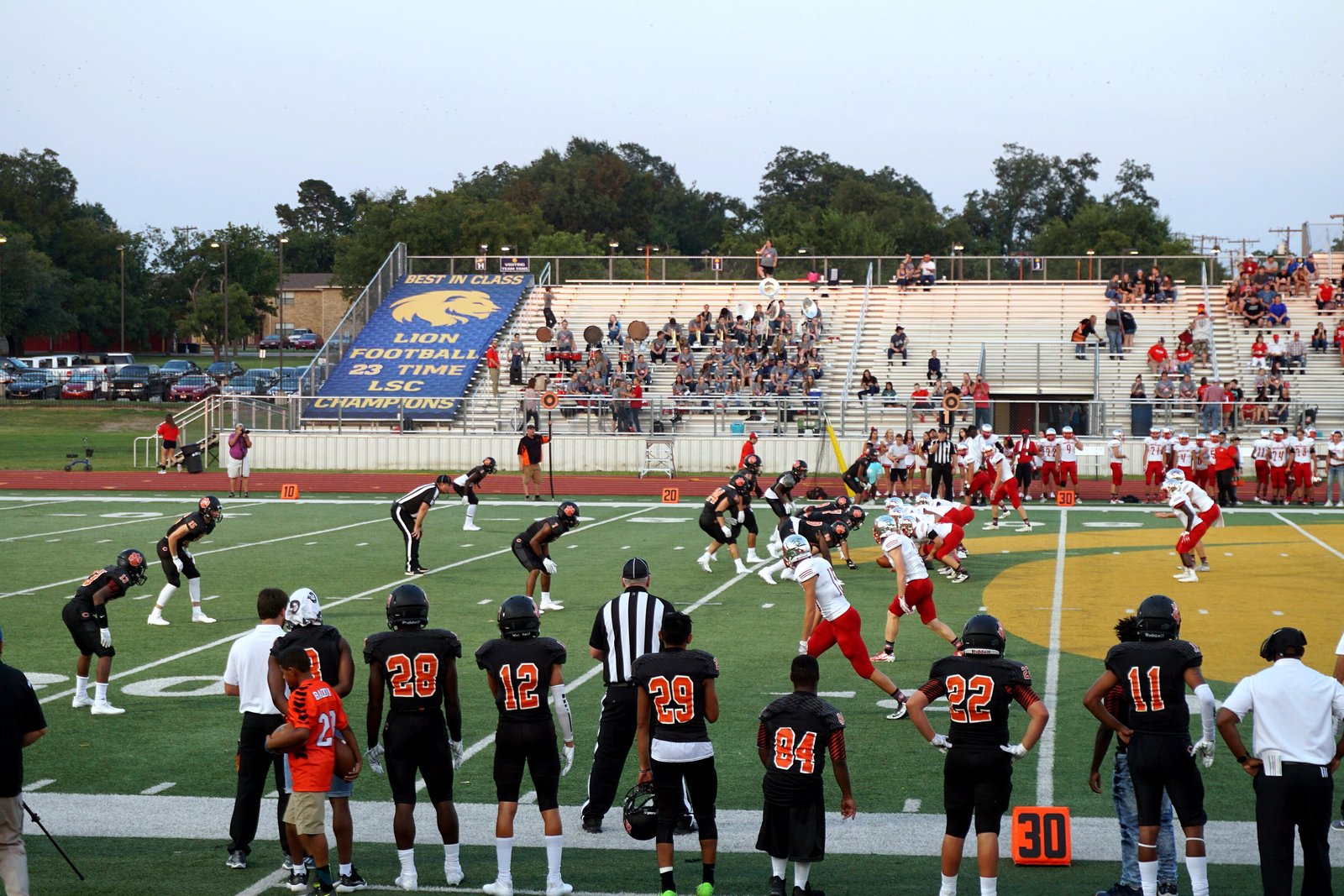 High school football players in dark and white uniforms line up at the line of scrimmage under stadium lights, in a file photo.