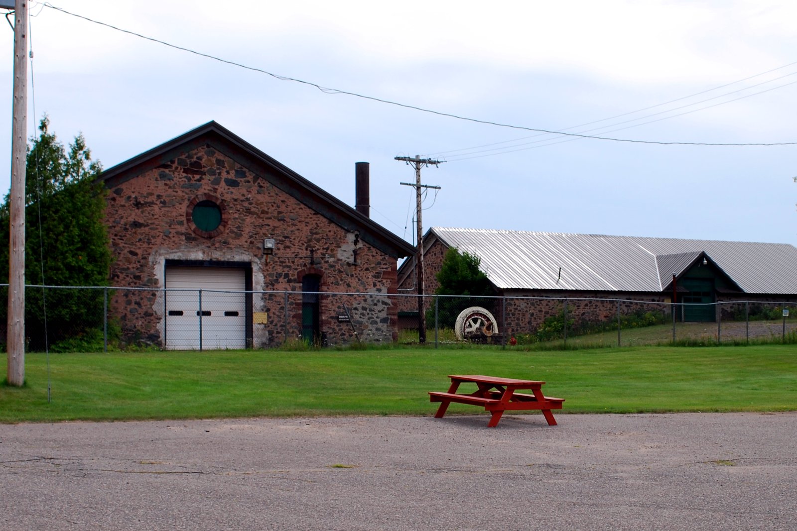Old brick and stone mine buildings and a grassy yard under a hazy sky at the Cliffs Shaft Mine site in Ishpeming.