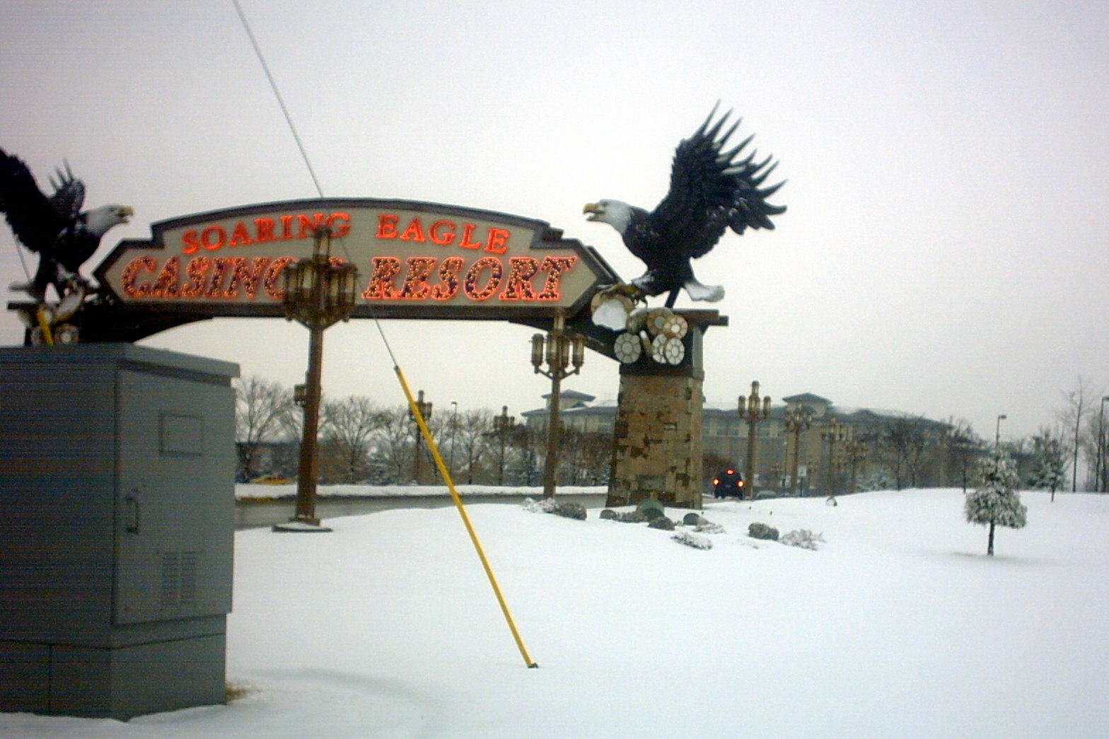 A snowy entrance sign for Soaring Eagle Casino and Resort, flanked by two large eagle sculptures, under a gray sky.