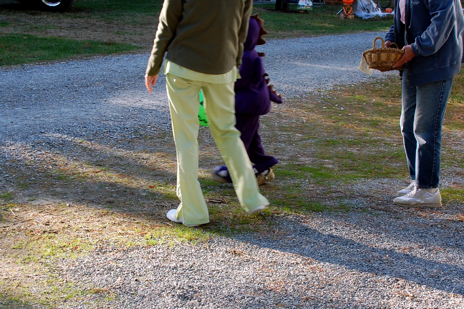 Children in Halloween costumes walk a campground road at dusk while trick-or-treating.