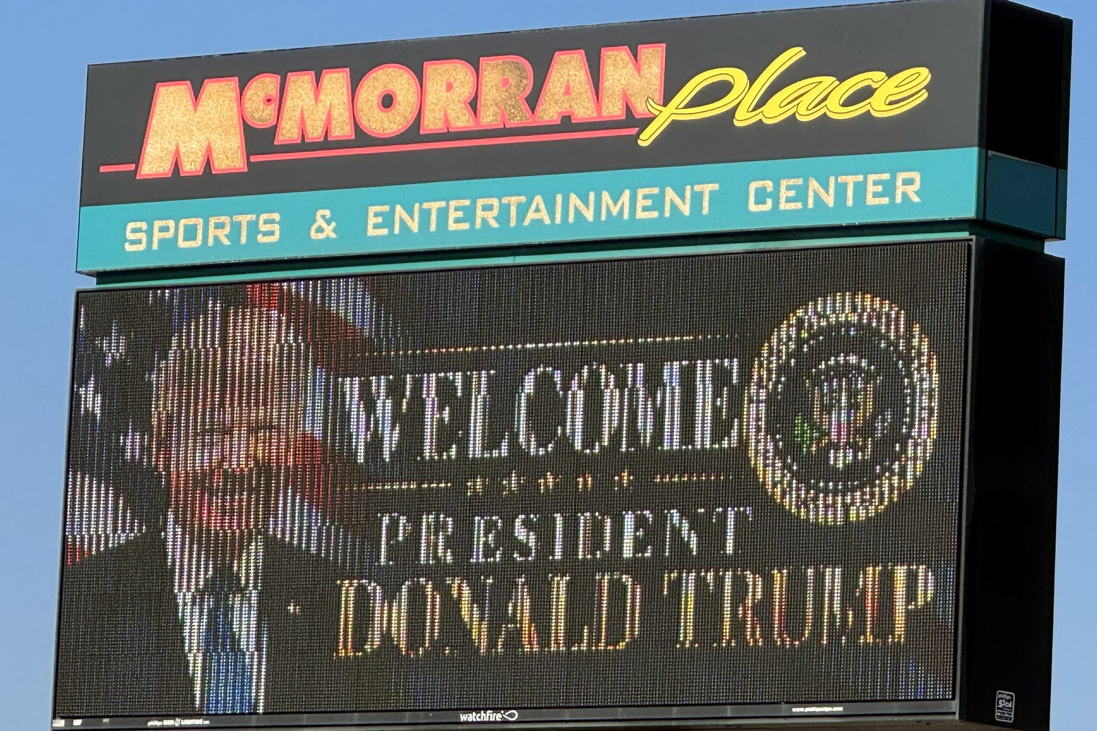 The McMorran Place Sports and Entertainment Center sign in Port Huron, its video board reading Welcome President Donald Trump beside the presidential seal, under a blue sky.