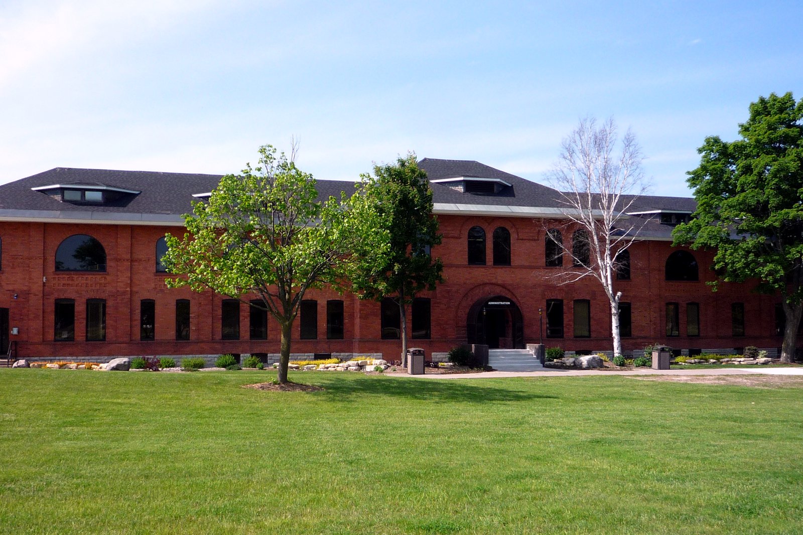 A long red-brick building with white trim and a lawn, the Lake Superior State University administration building.