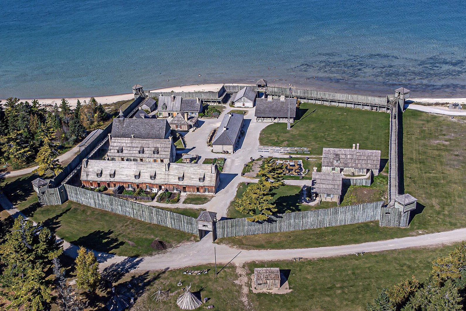 Aerial view of the reconstructed wooden stockade and buildings of Colonial Michilimackinac beside the Straits of Mackinac in October.