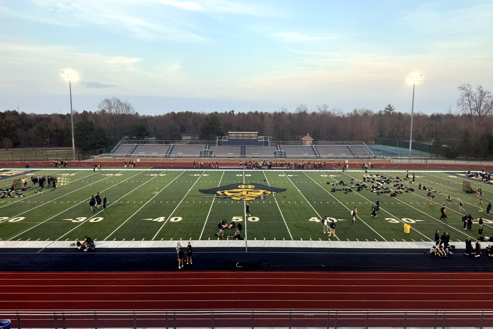 An empty high school football field with goal posts and bleachers under a clear sky in Grand Haven, Michigan.