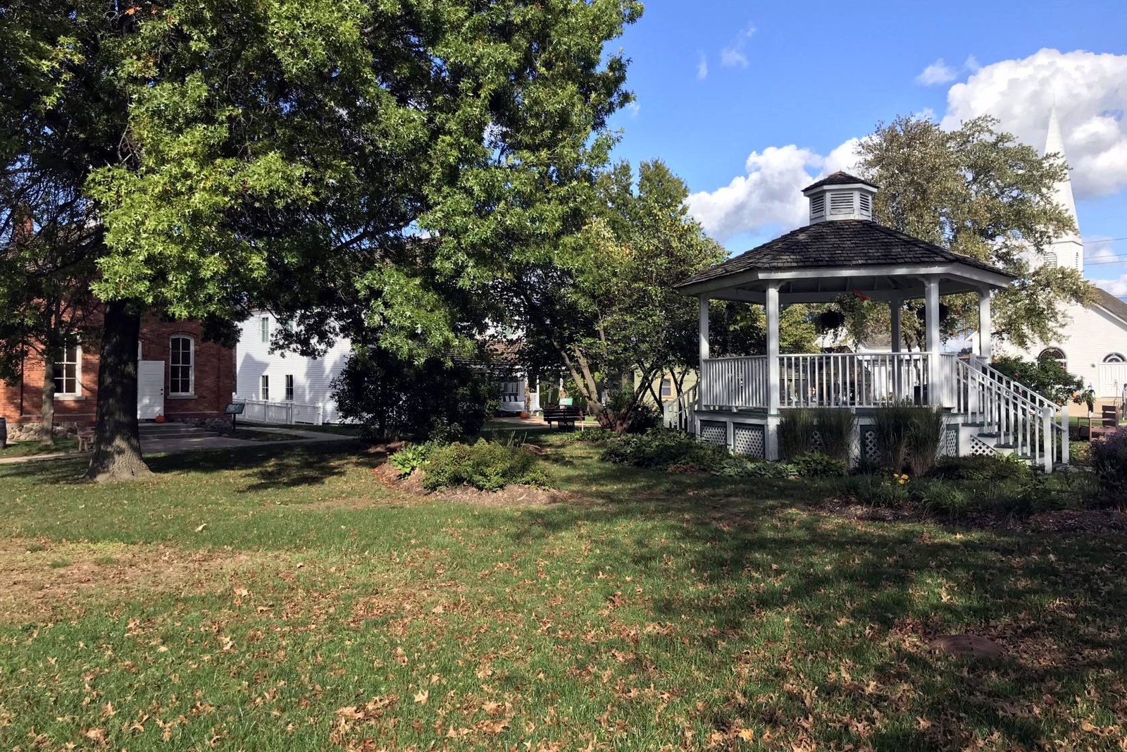Historic wooden buildings and a gravel path at Troy Historic Village under a clear sky.
