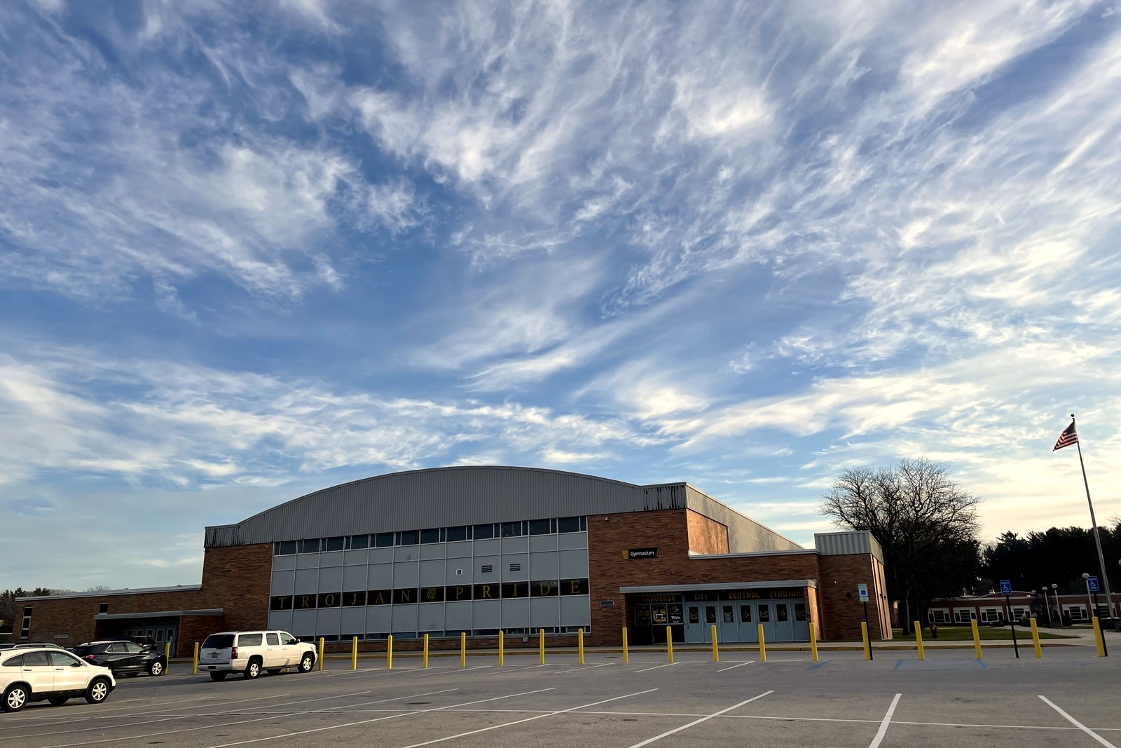 Traverse City Central High School’s brick building and parking lot under a wide, streaky sky.