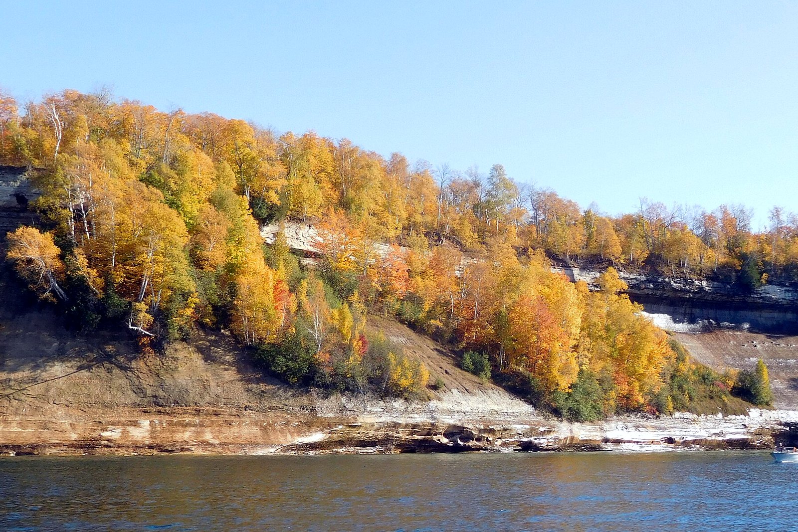 Pale cliffs topped with yellow and orange birch and maple trees above the water at Pictured Rocks National Lakeshore.