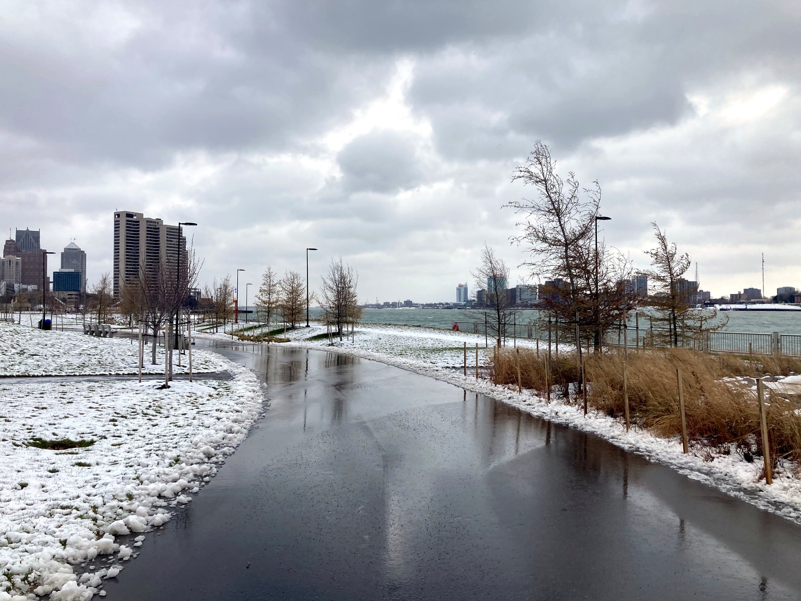 A path through Ralph C. Wilson, Jr. Centennial Park along the Detroit River, with the skyline beyond the water.